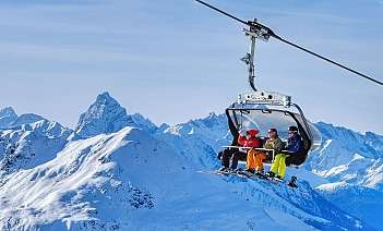 Skiers on a chairlift Group of skiers riding a chairlift in snowy mountains.