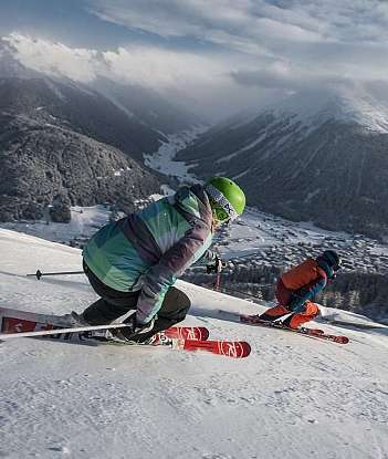 Skiers on a snowy slope Two skiers navigating a snowy mountain slope with a scenic backdrop.