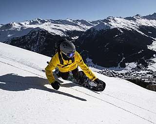 Snowboarder on a snowy slope A snowboarder in a yellow jacket riding down a snowy mountain.