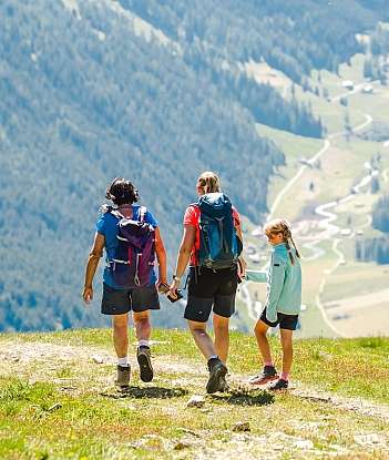 Family Hiking in Nature Three hikers walking on a mountain trail with scenic views.
