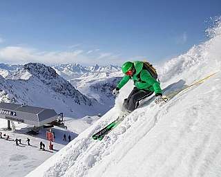 Skier on snowy mountain slope A skier descends a snowy slope with mountains in the background.